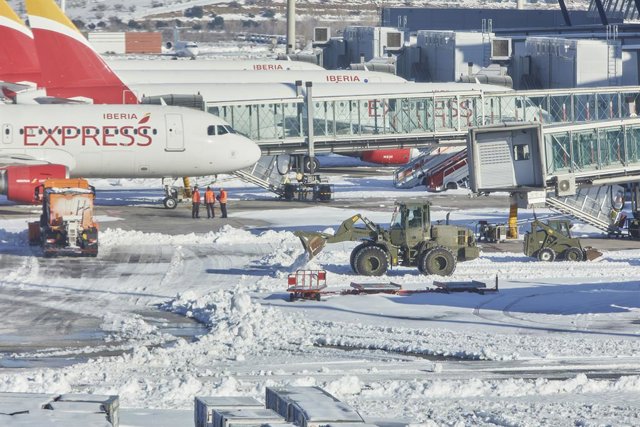Varias excavadoras de la Unidad Militar de Emergencias (UME) trabajan para quitar la nieve y el hielo de la pista del aeropuerto Madrid-Barajas Adolfo Suárez, en Madrid (España), a 12 de enero de 2021.  