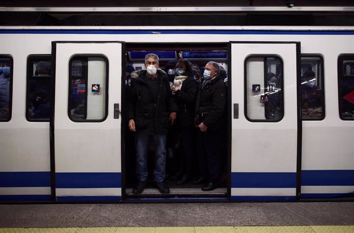Viajeros en un andén de metro lleno de gente a su paso por la estación de Atocha Renfe