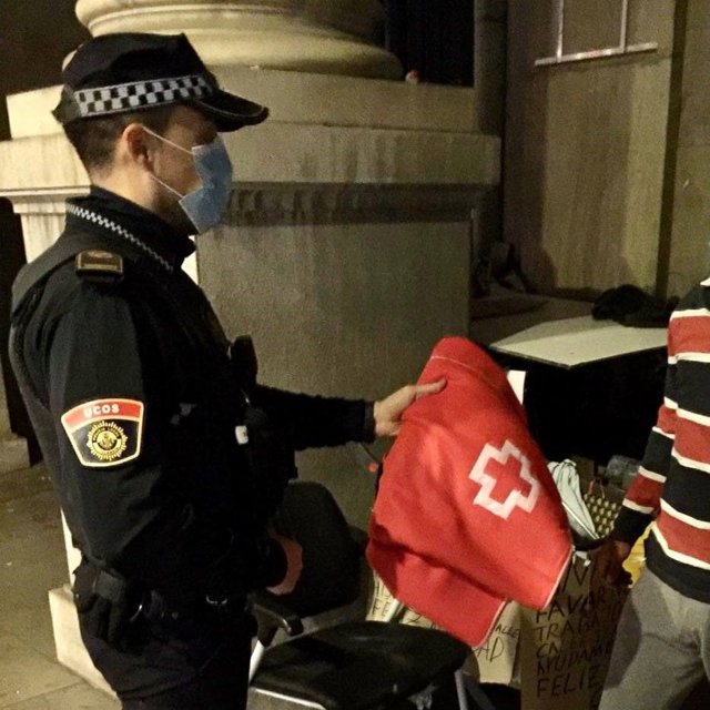 Un agente de la Policía Local de València atiende a una persona sin hogar (archivo)