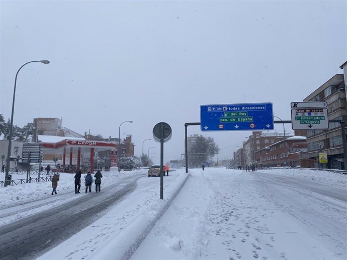 Varias personas caminan por la calzada completamente cubierta de nieve del Paseo de Extremadura a la altura de Batán 