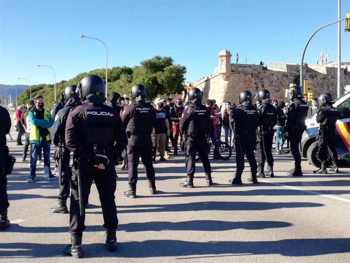 Policías ante los manifestantes de la concentración no autorizada por delegación del Gobierno y contra las medidas del Govern anticovid