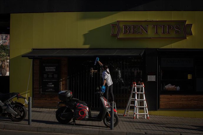 Una mujer limpia la fachada de un restaurante, a 23 de noviembre de 2020.  