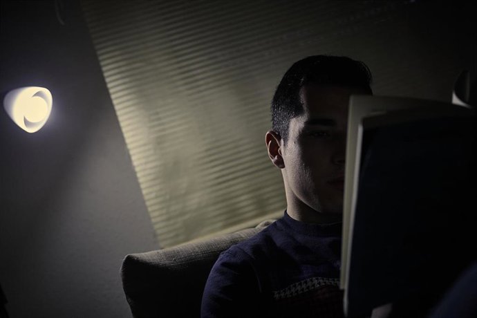 Un chico lee un libro bajo la luz de una lámpara en Madrid (España), a 12 de enero de 2021
