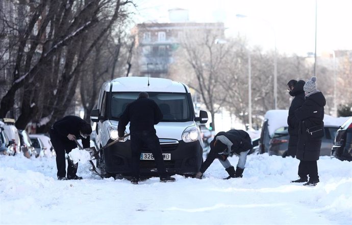 Vecinos del barrio de Pueblo Nuevo ayudan a un conductor a sacar su coche de la nieve, en Madrid (España), a 13 de enero de 2021.   Madrid sigue cubierto de nieve cinco días después de la gran nevada provocada por el paso de la borrasca Filomena. El A