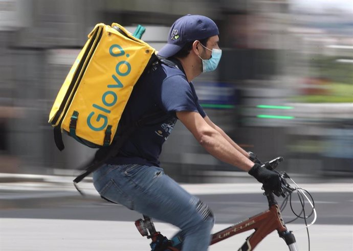 Un repartidor de Glovo monta una bicicleta durante su jornada laboral