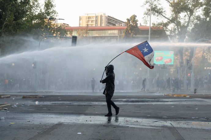 08 January 2021, Chile, Santiago: A man waves the Chilean flag in front of the water cannons of the police car during a protest against the police and the government of the Chilean President Sebastian Pinera. Photo: Matias Basualdo/ZUMA Wire/dpa
