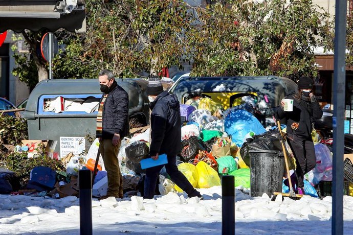 Dos personas pasan al lado de un cúmulo de residuos en una vía 