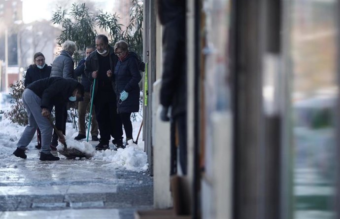 Vecinos del barrio de Pueblo Nuevo ayudan a quitar nieve y hielo de una vía,