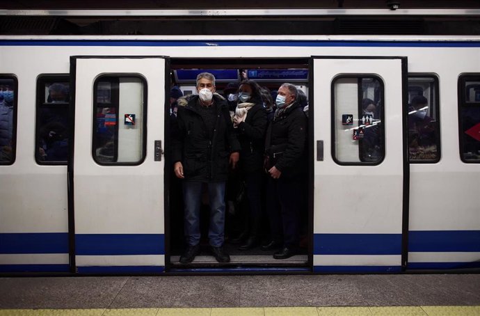 Viajeros en un andén de metro lleno de gente a su paso por la estación de Atocha Renfe, en Madrid (España).
