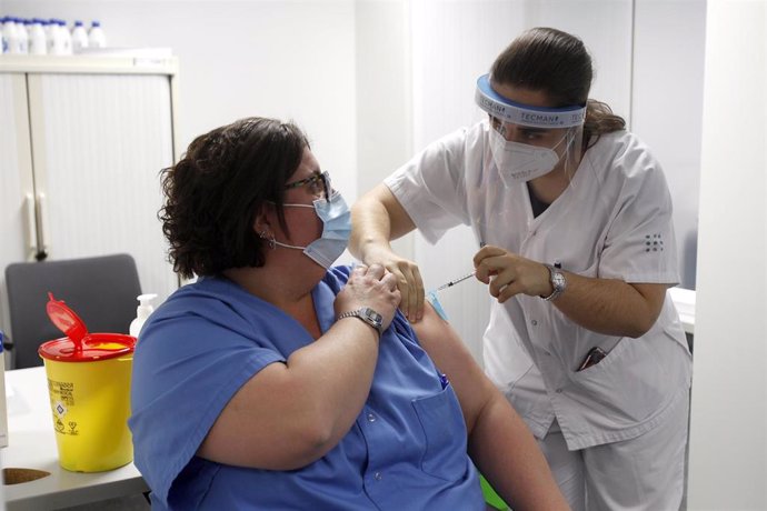 Una enfermera administra la vacuna Pfizer-BioNtech contra el COVID-19 a una profesional sanitaria en el Hospital Son Espases de Palma de Mallorca, en Mallorca, Islas Baleares (España), a 13 de enero de 2021. Baleares ha arrancado este miércoles la vacun