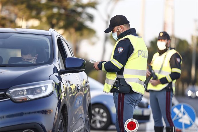 21 December 2020, Italy, Rome: A police officer checks motorists at a checkpoint at the Roma Nord toll plaza. From 21 December to 6 January, it is forbidden to travel between different Italian regions in order to contain the spread of the coronavirus. P