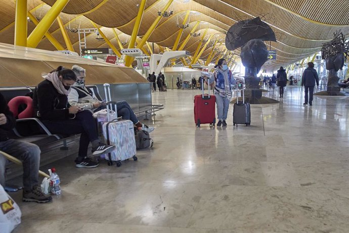 Varios pasajeros esperan sentados en los asientos de la Terminal 4 del aeropuerto Madrid-Barajas Adolfo Suárez