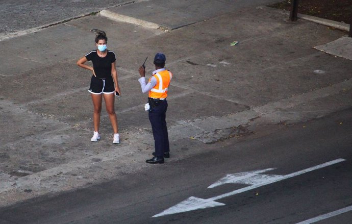 30 August 2020, Cuba, Havana: A policeman talks to a woman wearing a face mask at a checkpoint, a curfew in Havana will be imposed from 1 to 15 September 2020 due to an increase in new coronavirus cases. Photo: Guillermo Nova/dpa