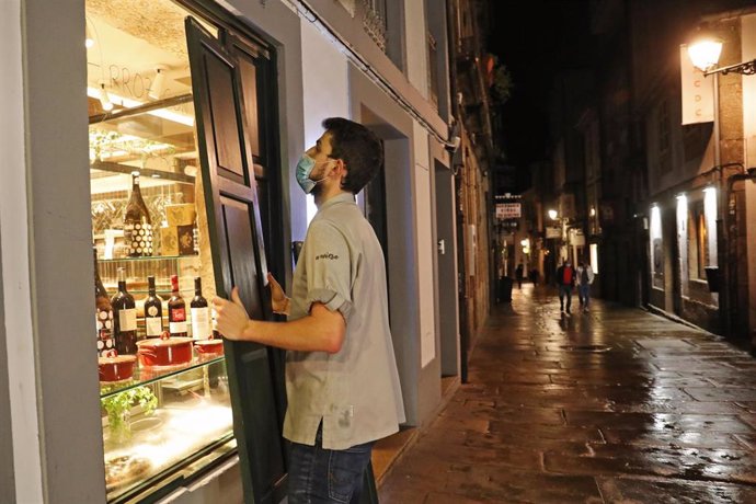 Un camarero protege su establecimiento a la hora del cierre por las medidas ordenadas por la crisis del Covid-19, en Santiago de Compostela, Galicia, (España), a 6 de noviembre. 