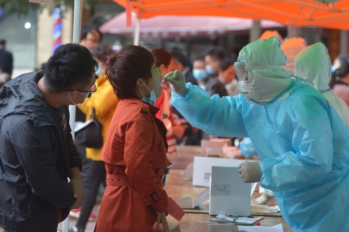 12 October 2020, China, Qingdao: A health worker takes a swab from a woman for the coronavirus test, after 9 people were found infected with the coronavirus (COVID-19) in Qingdao. Photo: -/TPG via ZUMA Press/dpa