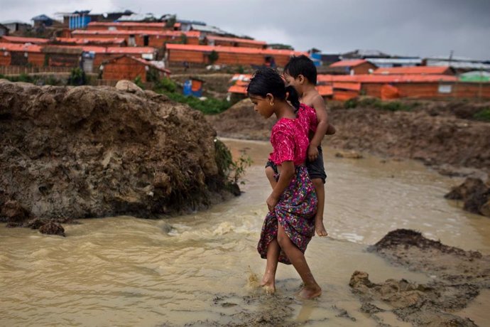 Una niña roghingya lleva a su hermano en un asentamiento de refugiados en Cox Bazar