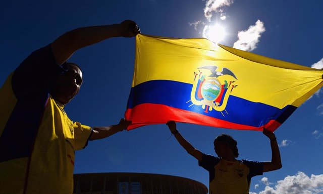 Dos hombres sosteniendo la bandera de Ecuador.