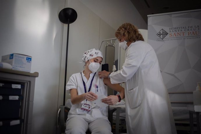 Una enfermera vacuna a un profesional sanitario con la vacuna de Pfizer-BioNtech contra el COVID-19 en el Hospital de la Santa Creu i Sant Pau de Barcelona