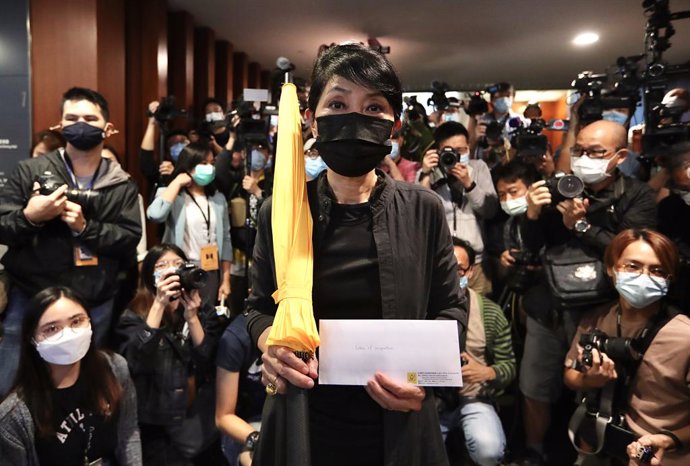 12 November 2020, China, Hong Kong: Pro-Democratic lawmaker Claudia Mo (C)holds a yellow umbrella and resignation letter on her way to hand in the letter in the legislative council. A group of 15 Hong Kong politicians resigned en masseon Wednesday in 