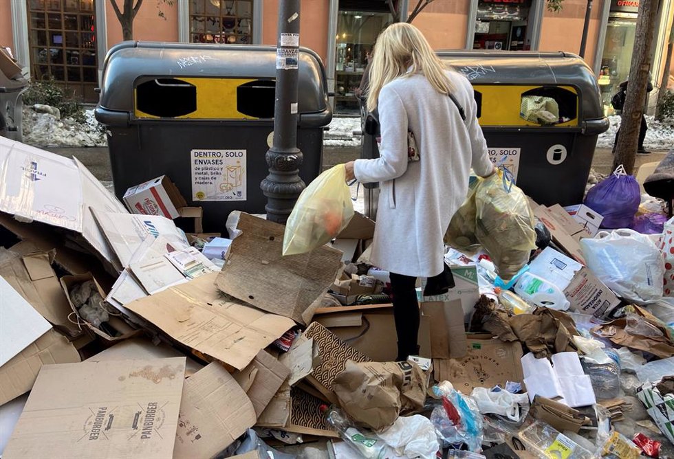 Una mujer tira dos bolsas de basura donde hay acumuladas otras tantas decenas de bolsas en un punto de Alonso Martínez, en Madrid (España), a 15 de enero de 2021. Desde que el Ayuntamiento de Madrid desplegara el dispositivo de retirada de basura este m
