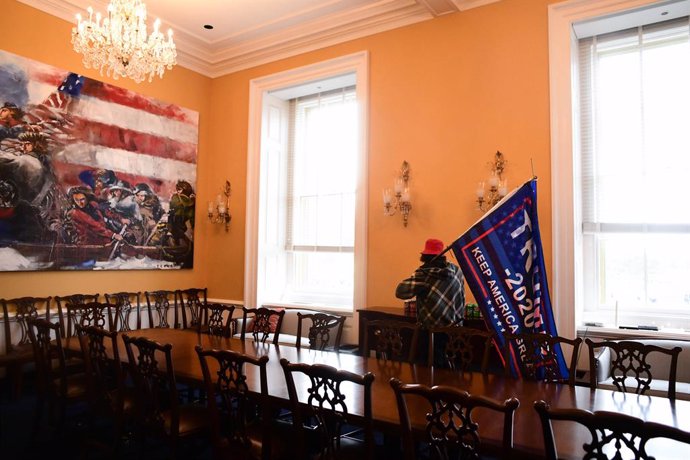 06 January 2021, US, Washington: A protester holds a Trump campaign flag as he walks inside an office of the USCapitol after supporters of US President Donald Trump stormed the building where lawmakers were due to certify president-elect Joe Biden's wi