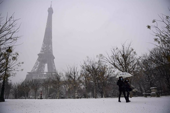 16 January 2021, France, Paris: A couple walks with an umbrella during snowfall in front of the Eiffel Tower. Photo: Martin Bureau/AFP/dpa