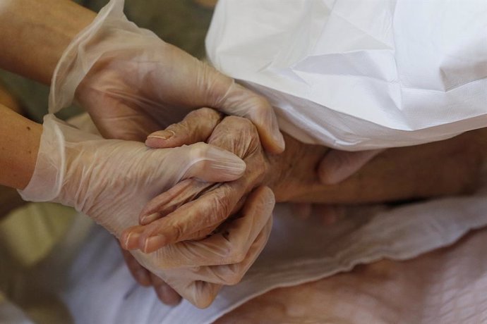 13 January 2021, Italy, Rome: A medic holds hands with an elderly woman as she receives her dose of the Biontech/Pfizer COVID-19 vaccine at a retirement Home. Photo: Cecilia Fabiano/LaPresse via ZUMA Press/dpa