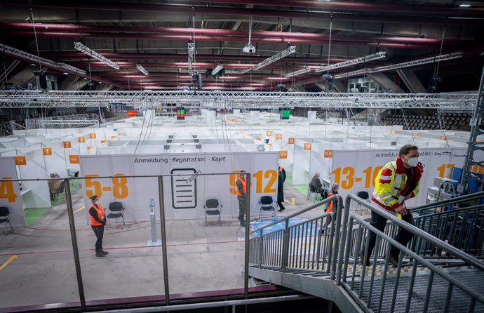 14 January 2021, Berlin: Helpers walk through the partitions of Berlin's second newly opened vaccination centre at the Erika Hess Ice Age Stadium. Photo: Kay Nietfeld/dpa-Pool/dpa