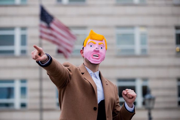 16 January 2021, Berlin: A man wearing a mask meant to represent US outgoing President Donald Trump with a pig's nose dances in front of the US Embassy for a video of a satirical project by a design student. Photo: Christoph Soeder/dpa