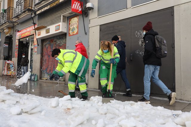 Dos operarias de limpieza trabajan en la retirada de la nieve y el hielo de la calle Argumosa ubicada en Lavapiés