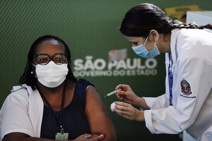 17 January 2021, Brazil, Sao Paulo: Brazilian nurse Monica Calazans (L) receives his dose of the Coronavirus (Covid-19) vaccine by a health worker during a vaccination campaign. Brazil's National Health Surveillance Agency has granted emergency approval
