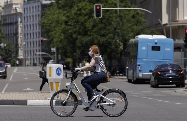Una mujer protegida con mascarilla monta en una bicicleta de BiciMAD 