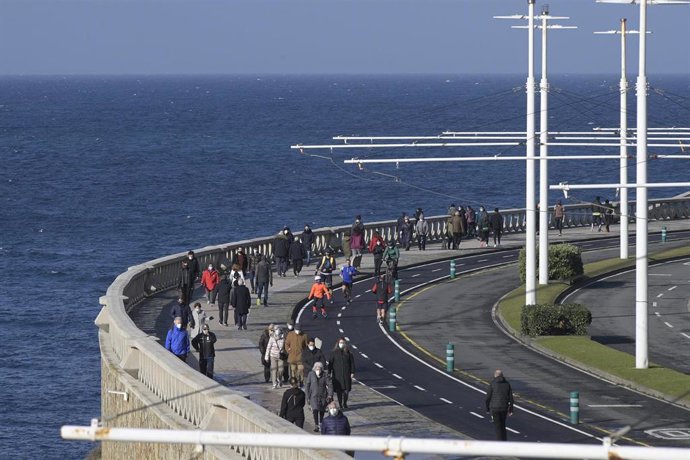 Varias persoas camiñan por un paseo marítimo na Coruña
