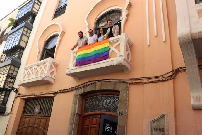 Dirigentes del PSOE con la bandera arco iris en la fachada de la sede provincial.