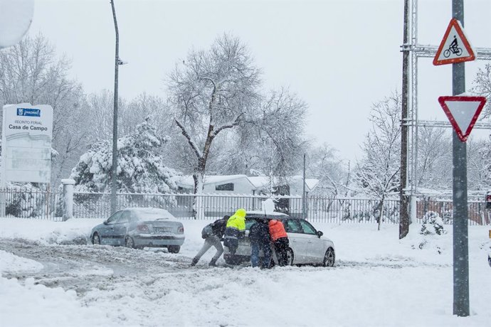 Varias personas ayudan a sacar un coche atrapado por la nieve durante la gran nevada provocada por la borrasca Filomena.