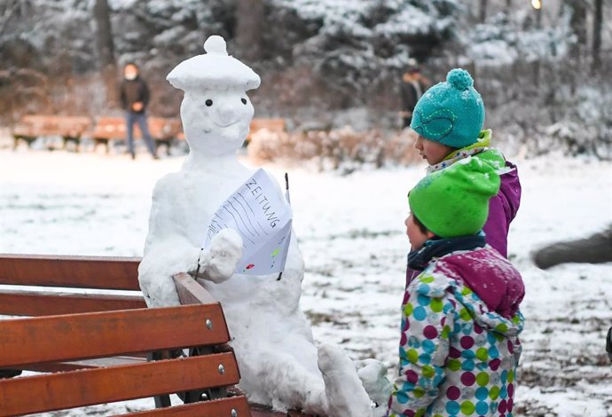 Dos niños junto a un muñeco de nieve en Frankfurt, Alemania