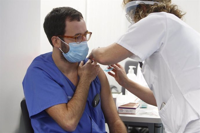 Una enfermera administra la vacuna Pfizer-BioNtech contra el COVID-19 a un profesional sanitario en el Hospital Son Espases de Palma.