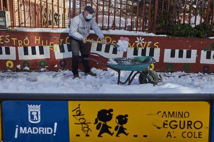 Un familiar colabora en la limpieza del hielo y la nieve en las inmediaciones del colegio Amadeo Vives tras la gran nevada por el paso de la borrasca 'Filomena', en Madrid, (España), a 16 de enero de 2021. El paso del temporal ha provocado que los coleg