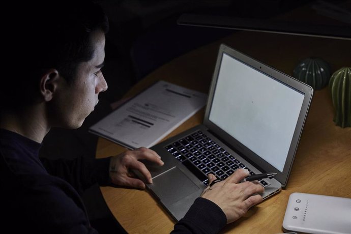 Un estudiante utiliza el ordenador para realizar tareas en casa, foto de archivo