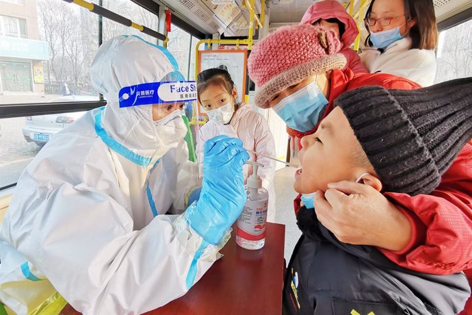 23 December 2020, China, Dalian: A health worker takes a swab from a child for a coronavirus test at Ganjingzi district during a mass testing campaign. Photo: Liu Debin/SIPA Asia via ZUMA Wire/dpa