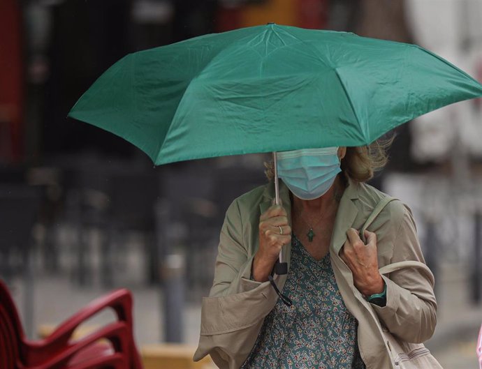 Una mujer se protege de la llovizna bajo un paraguas durante el aviso amarillo activado por la Agencia Estatal de Meteorología (Aemet), 