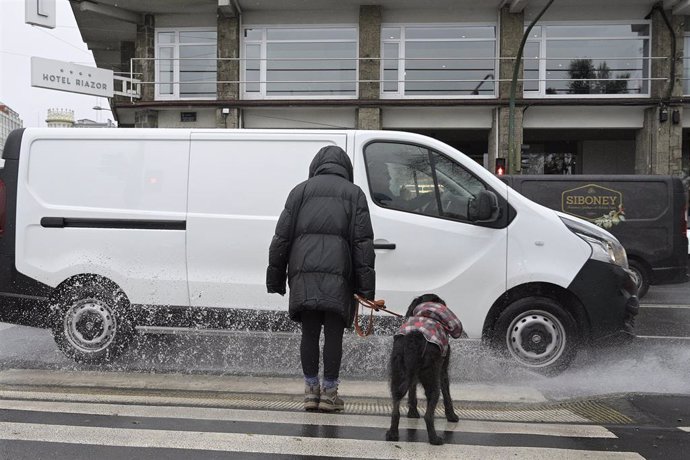 Unha muller espera co seu can antes de cruzar por un paso de peóns da Coruña, Galicia (España)