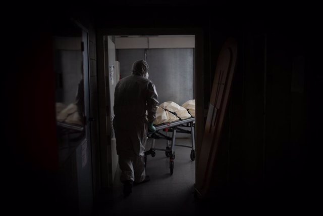 Un operario del Crematorio de Girona totalmente protegido traslada un ataúd de una víctima con Covid-19 a una cámara frigorífica para desinfectarlo antes de introducirlo en el horno crematorio. En Girona, Cataluña, (España), a 6 de mayo de 2020.