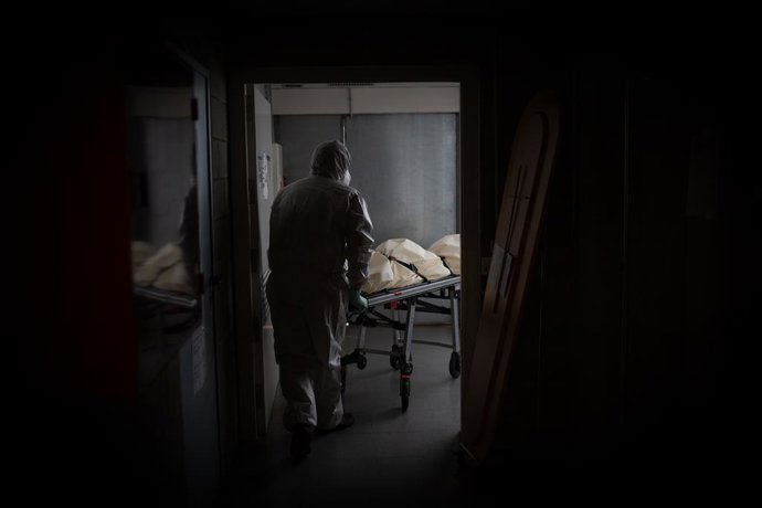 Un operario del Crematorio de Girona totalmente protegido traslada un ataúd de una víctima con Covid-19 a una cámara frigorífica para desinfectarlo antes de introducirlo en el horno crematorio, durante el día 53 del estado de alarma por la crisis del co