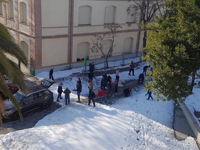 Familiares de alumnos colaboran en la limpieza de los accesos al colegio Vedruna, en Carabanchel