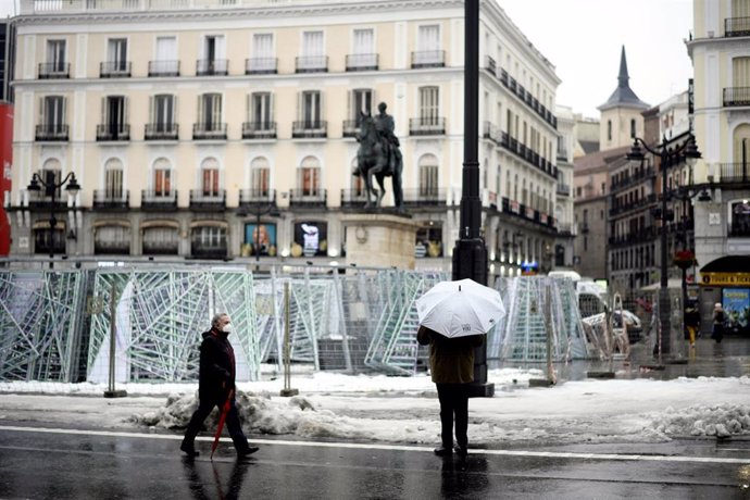 Una persona camina protegida por la Puerta del Sol el mismo día de la llegada del temporal Gaetán, en Madrid, (España), a 20 de enero de 2021. El temporal de nieve y posterior frío provocado por la borrasca 'Filomena' terminó ayer para dejar al tempor