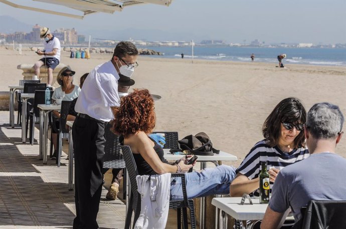 Diverses persones gaudixen en la terrassa d'un bar al costat de la platja després que el Ministeri de Sanitat autoritzara al fet que la totalitat de la Comunitat Valenciana passara en el seu conjunt a la fase 1 de la desescalada. Les terrasses dels rest