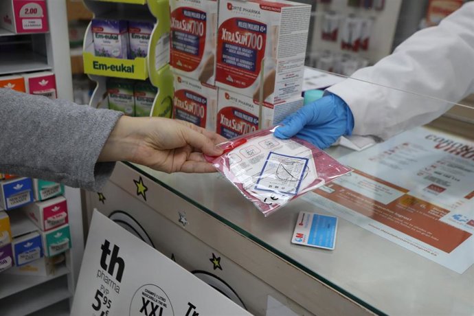 Un farmaceútico entrega a un cliente una mascarilla FFP2 modelo KN95.