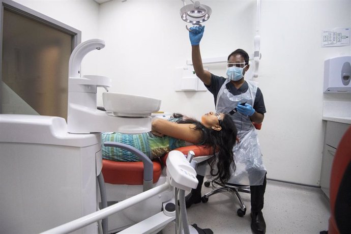 08 June 2020, England, London: Dentist Dr Roy Woodhoo wearing protective suit examines the first patient at Woodford Dental Care, as it reopens for the first time since the UK went into coronavirus lockdown. Photo: Victoria Jones/PA Wire/dpa