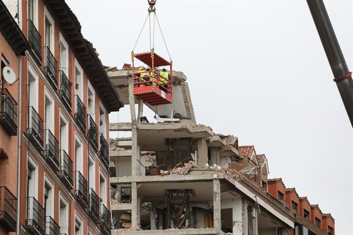 Varios operarios colgados de una grúa trabajan en la inspección ocular del edificio tras la explosión de ayer en la calle Toledo, en Madrid (España), a 21 de enero de 2021. La Policía Municipal de Madrid está retirando esta mañana los vehículos dañados 